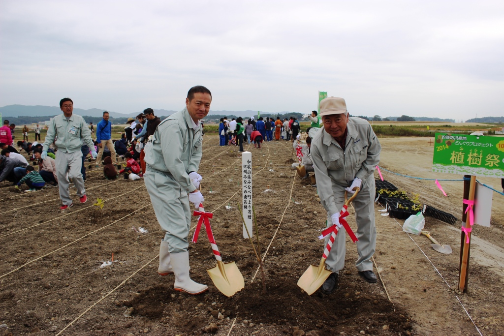 復興支援で来ていた越本進男さんと町長が一緒に記念スコップで植樹をしている写真